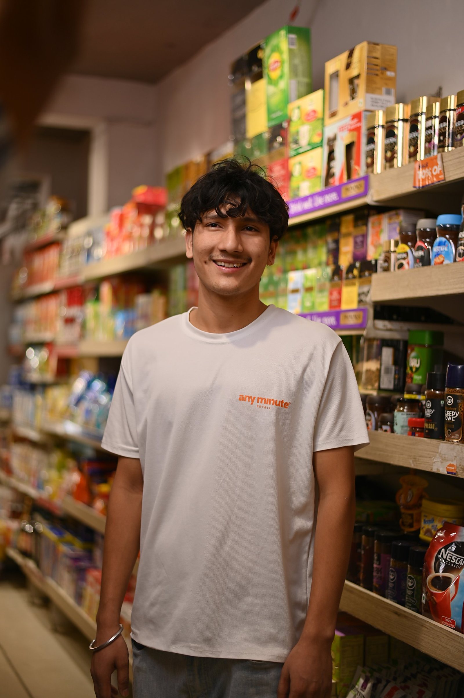 An Any Minute team member smiling in a stocked store aisle